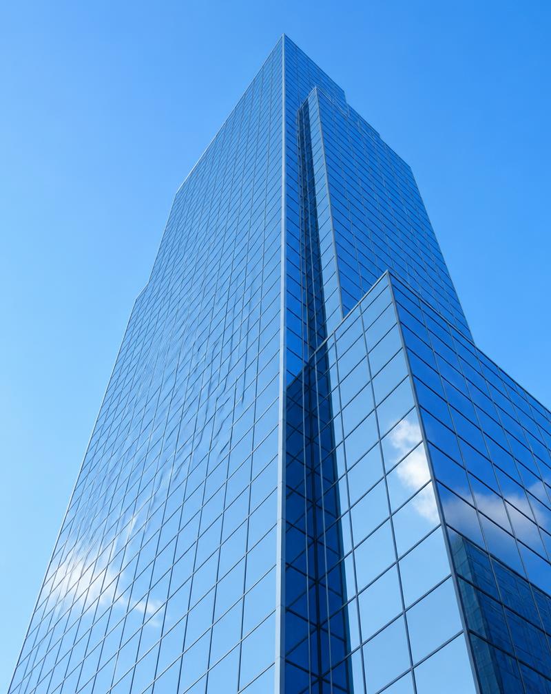 Glass facade of a corporate building reflecting the sky
